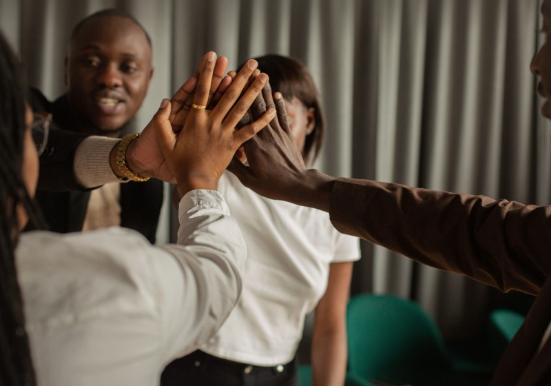 African professionals in a hands-in team huddle